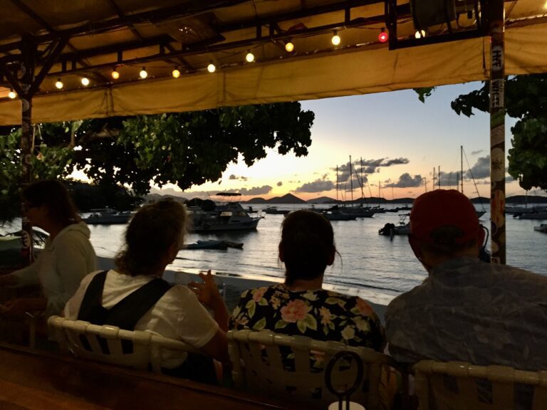 Three people watching the sunset by the sea